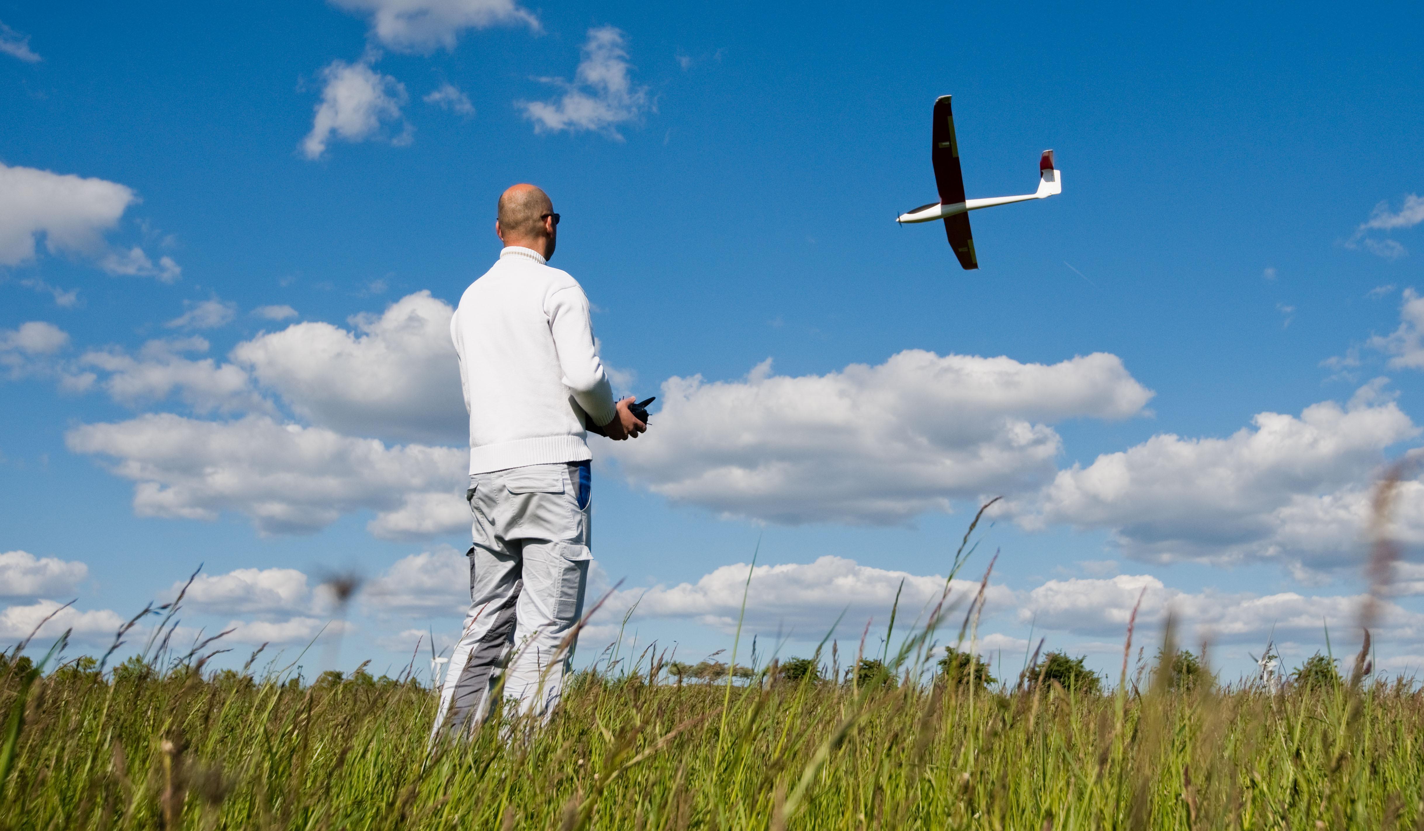 Ein Mann steuert einen Modellflieger auf einer Wiese (Symbolbild)