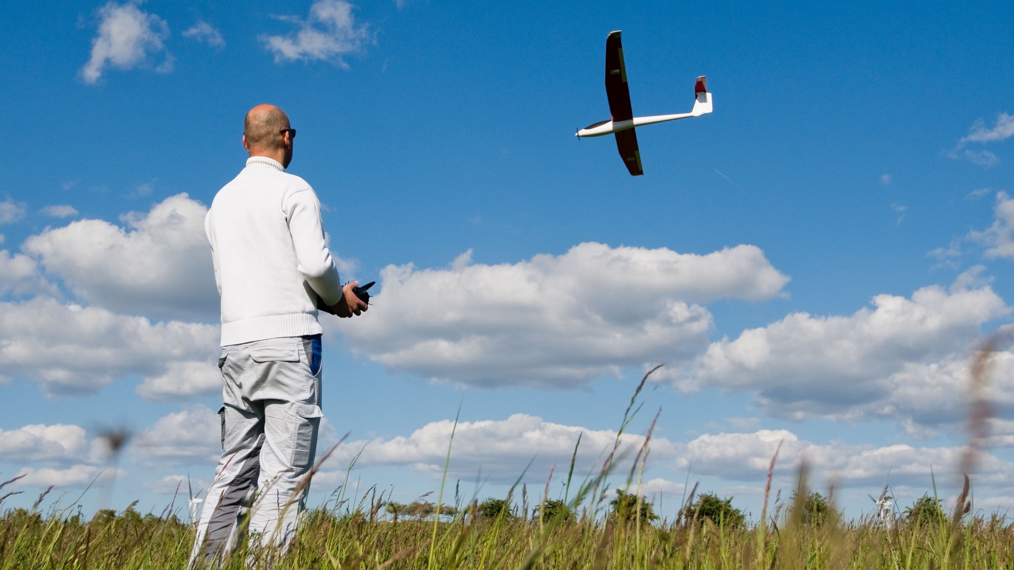 Ein Mann steuert einen Modellflieger auf einer Wiese (Symbolbild)