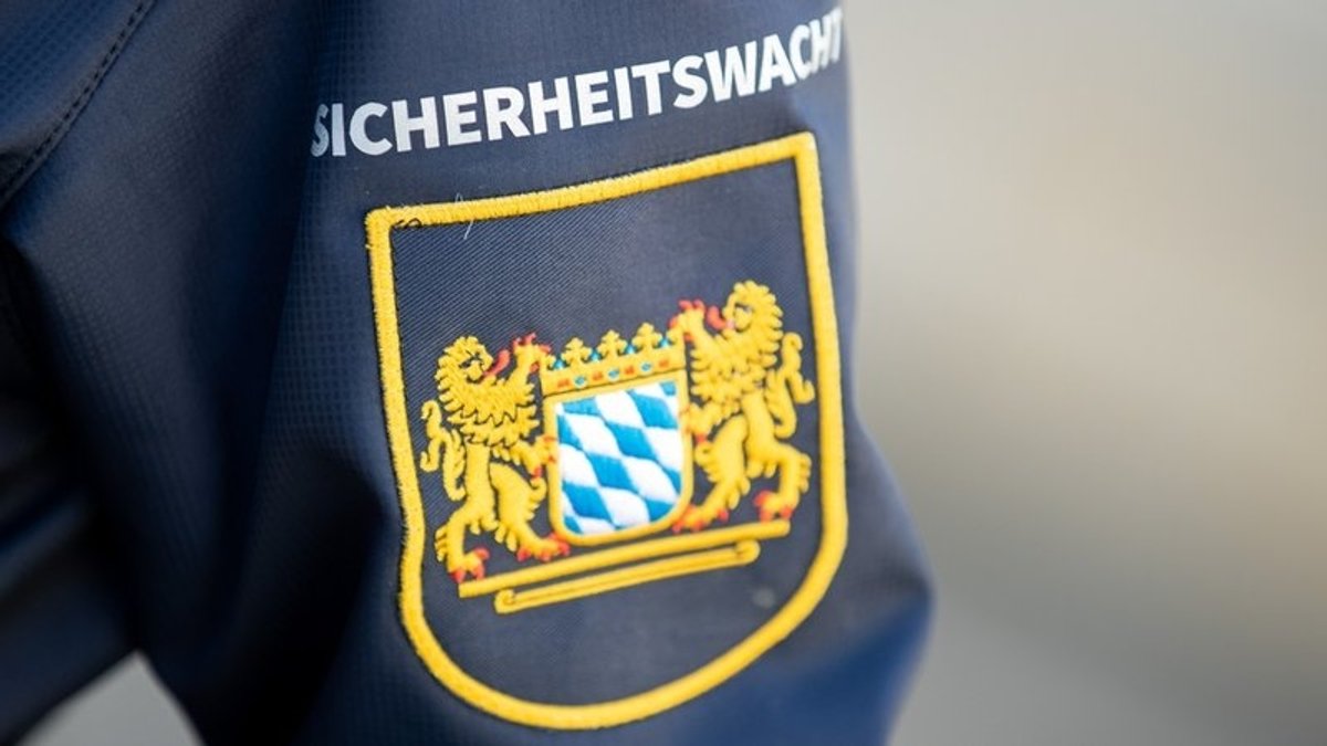 "Sicherheitswacht" steht auf einer Jacke, darunter das Wappen des Freistaats Bayern.