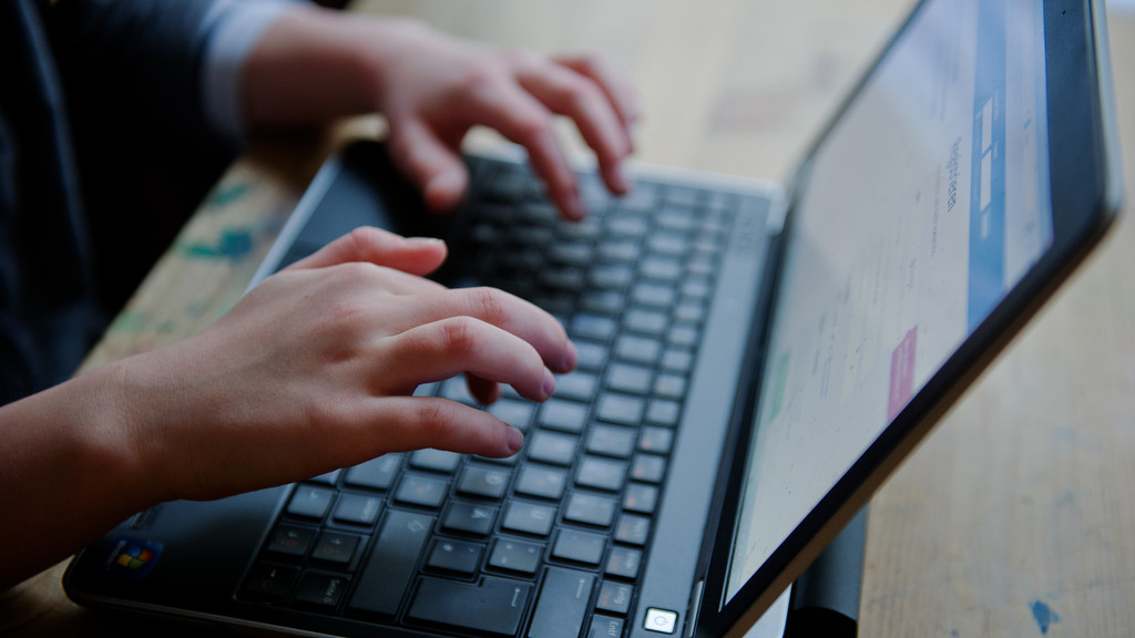 Ein Kind tippt an einem Laptop - Polizei Neu-Ulm warnt vor Cybergrooming