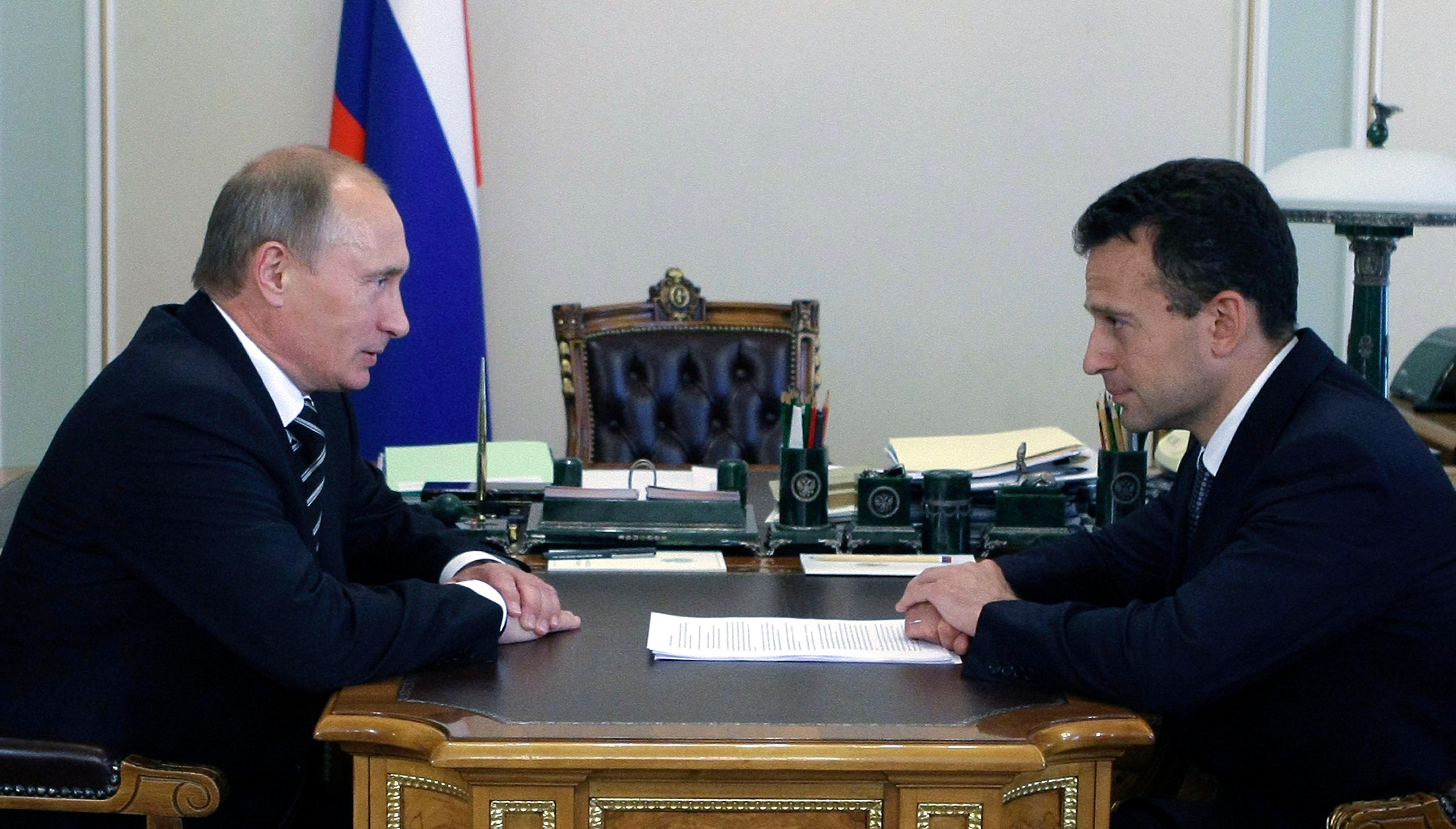 Beide sitzen sich an einem Schreibtisch gegenüber