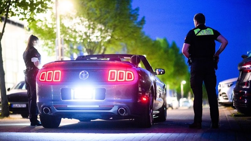 Ein Polizist und eine Polizistin kontrollieren ein Auto (Symbolbild)