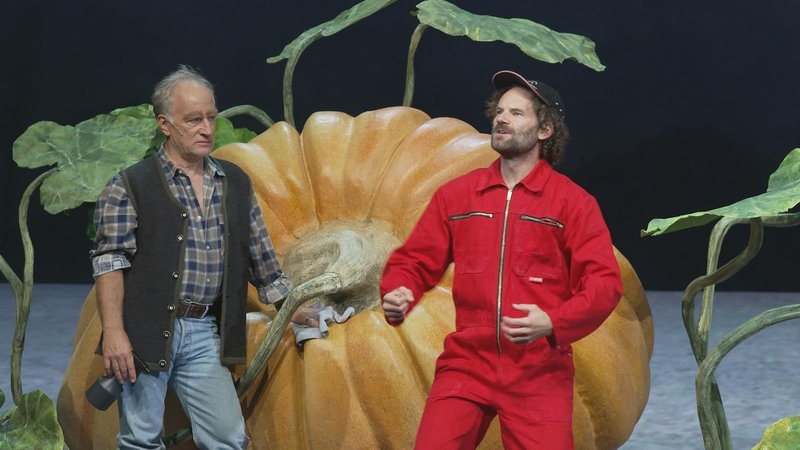 v.l.n.r.: Stefan Merki und Maxi Schafroth vor einem übergroßen Kürbis auf der Bühne der Münchner Kammerspielen im Musiktheater-Stück "Wachse oder weiche" | Bild: BR v.l.n.r.: Stefan Merki und Maxi Schafroth vor einem übergroßen Kürbis auf der Bühne der Münchner Kammerspielen im Musiktheater-Stück "Wachse oder weiche"