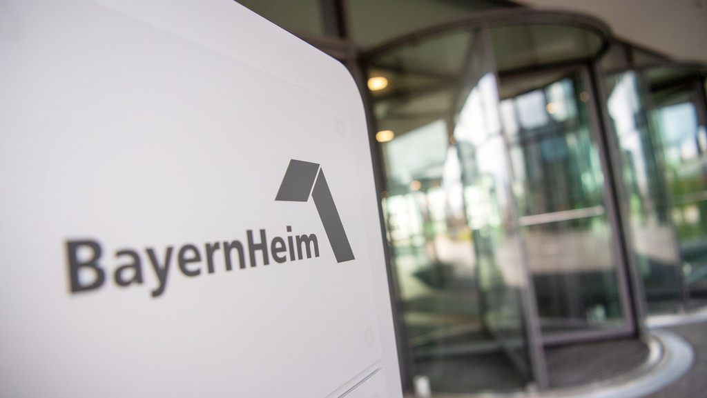 Das Logo der Bayernheim GmbH ist vor der Geschäftsstelle auf einem Schild abgebildet.