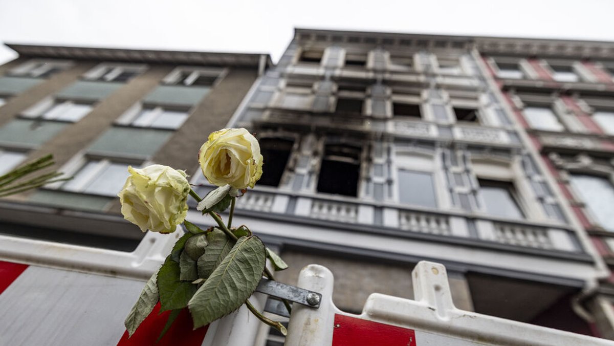 ARCHIV - 27.03.2024: Eine weiße Rose an einer Absperrbake vor dem Brandort in Solingen nach dem Pressestatement der Staatsanwaltschaft Wuppertal zum tödlichen Brand in Solingen. In dem Feuer waren vier Menschen ums Leben gekommen, mehrere wurden verletzt.