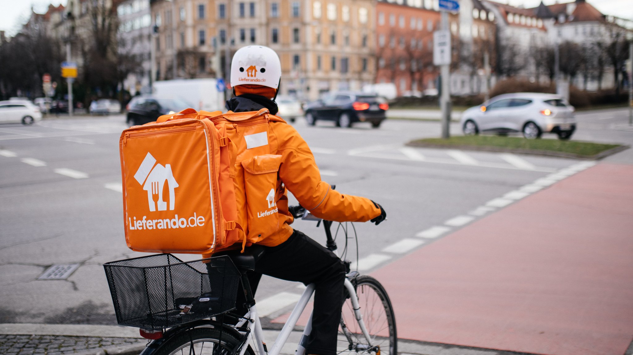 Ein Lieferandofahrer wartet an einer roten Ampel. 