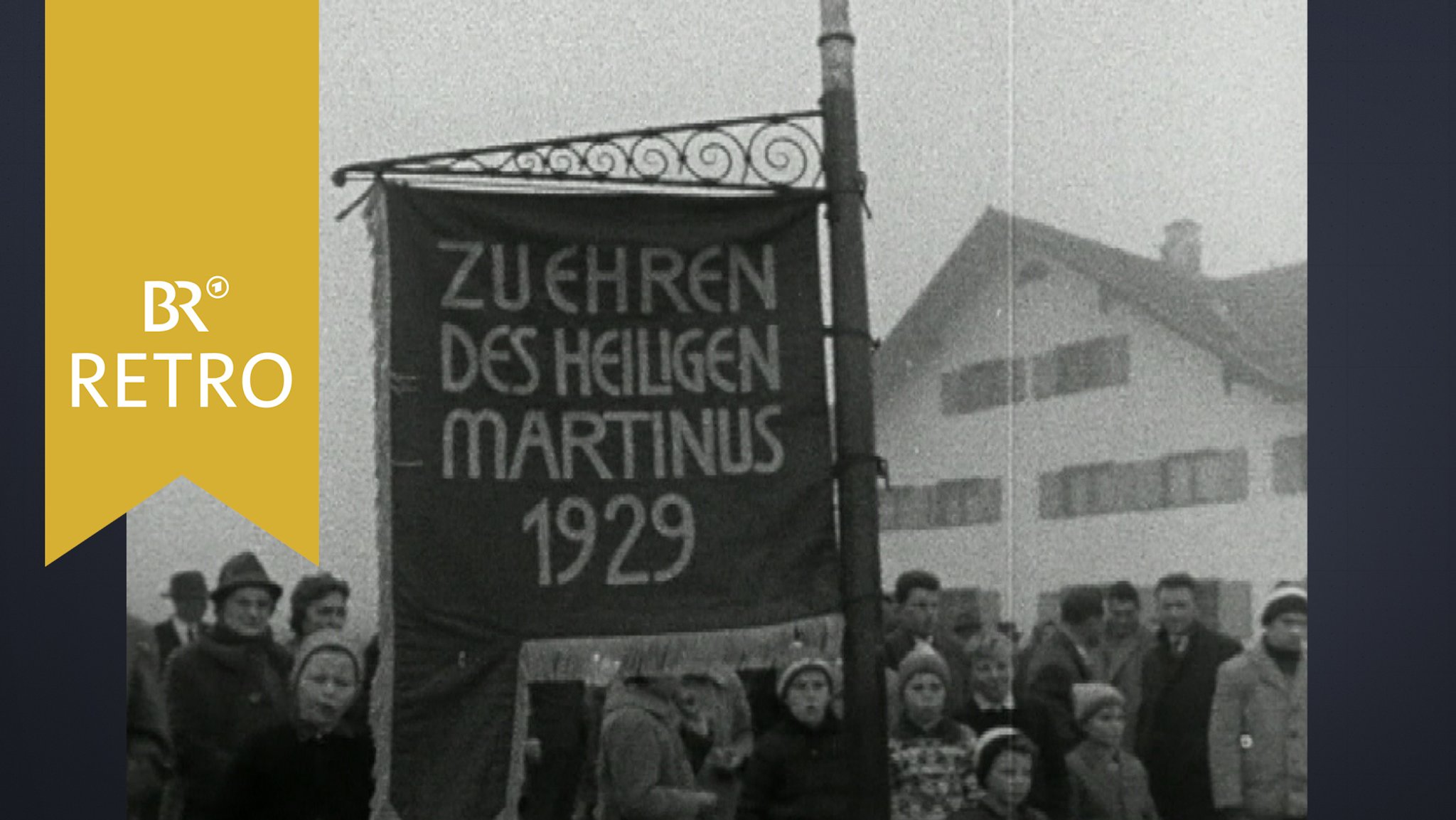 Zuschauer beim Martiniritt in Obergünzburg. Ein Junge hält eine Fahne mit der Aufschrift "Zu Ehren des Heiligen Martinus 1929