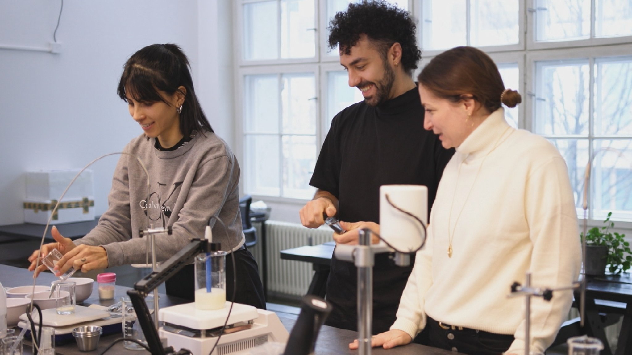 Forschende des Food-Start-ups Loyely Day Foods stehen im Labor. In verschiedenen Gefäßen werden Proteine auf ihre Schäumeigenschaften getestet