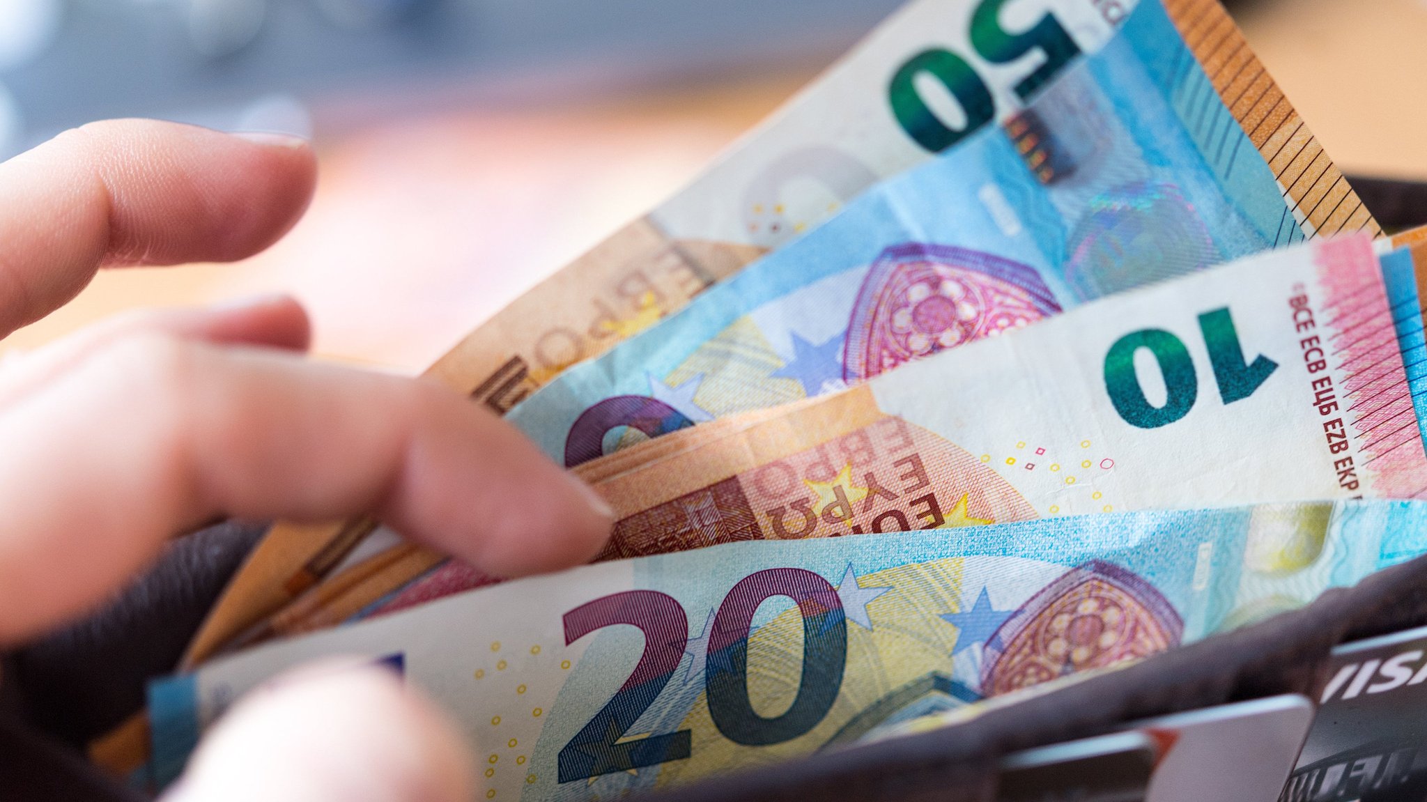  Eine Frau hält eine Geldbörse mit Banknoten in der Hand