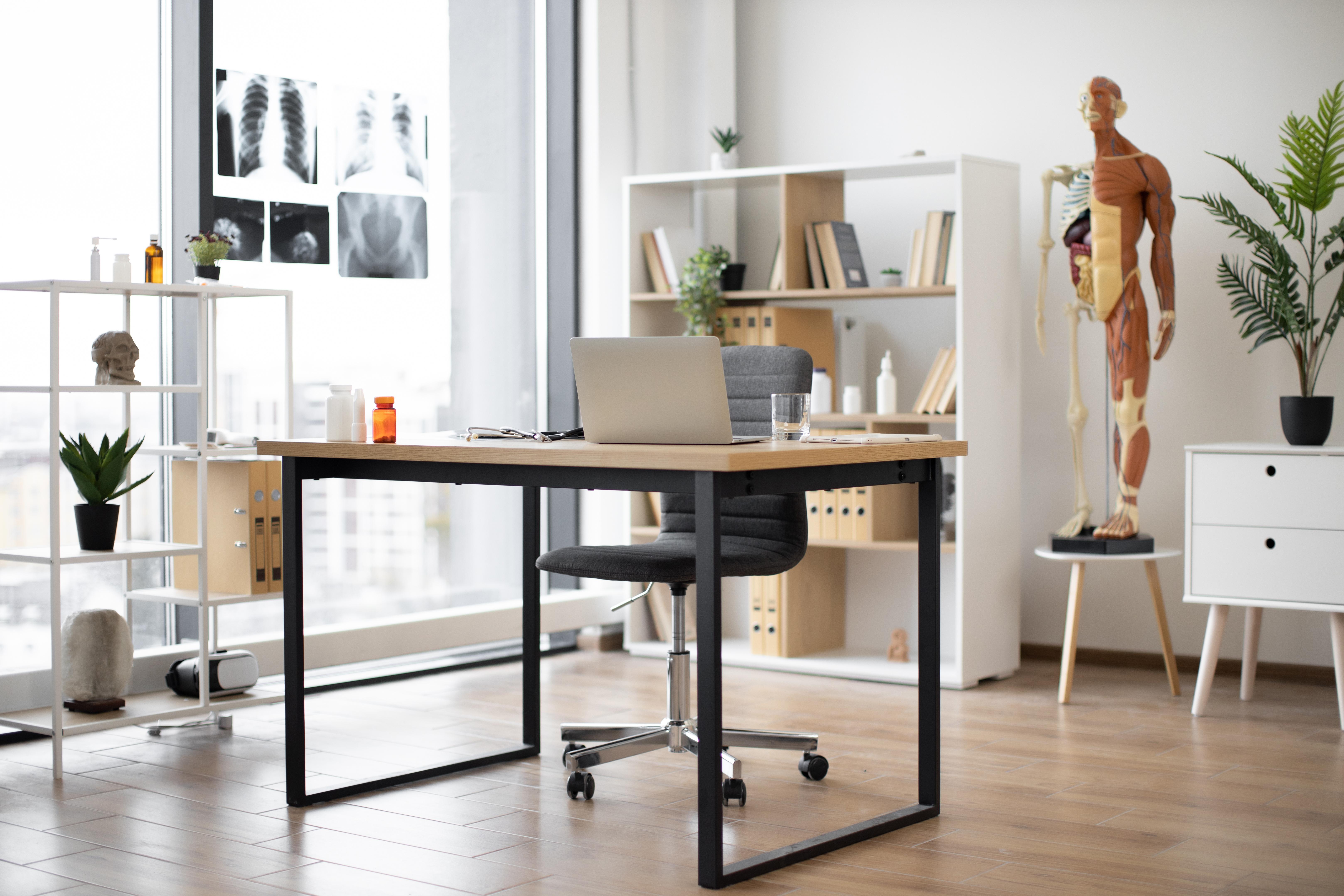 Ein helles und offenes Zimmer einer Arztpraxis, mit anatomischem Modell eines Menschen und diversen medizinischen Materialien (Symbolbild)