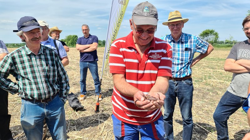 Lächelnde Männer stehen auf einem schlampig aussehenden Acker. Einer zeigt seine Hände, mit 40 großen Regenwürmer in der Hand. | Bild: BR / Ursula Klement Lächelnde Männer stehen auf einem schlampig aussehenden Acker. Einer zeigt seine Hände, mit 40 großen Regenwürmer in der Hand.