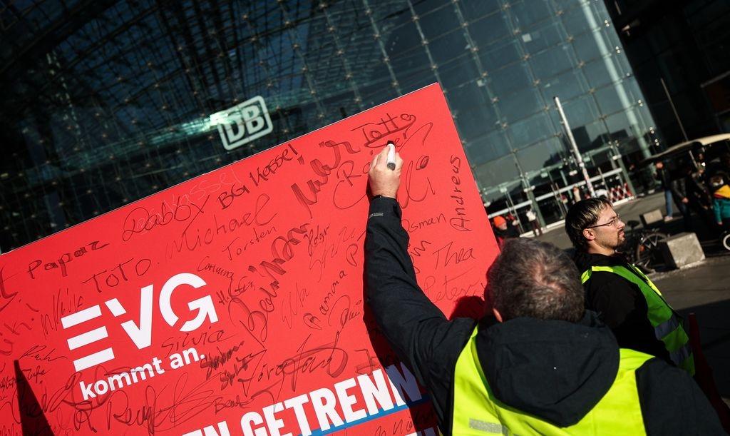 03.02.2025, Berlin: Ein Teilnehmer der Kundgebung unterschreibt auf einem Aufsteller mit EVG-Logo. Die Eisenbahn- und Verkehrsgewerkschaft (EVG) hatte zu einer Kundgebung vor dem Berliner Hauptbahnhof aufgerufen. Foto: Hannes P. Albert/dpa +++ dpa-Bildfunk +++