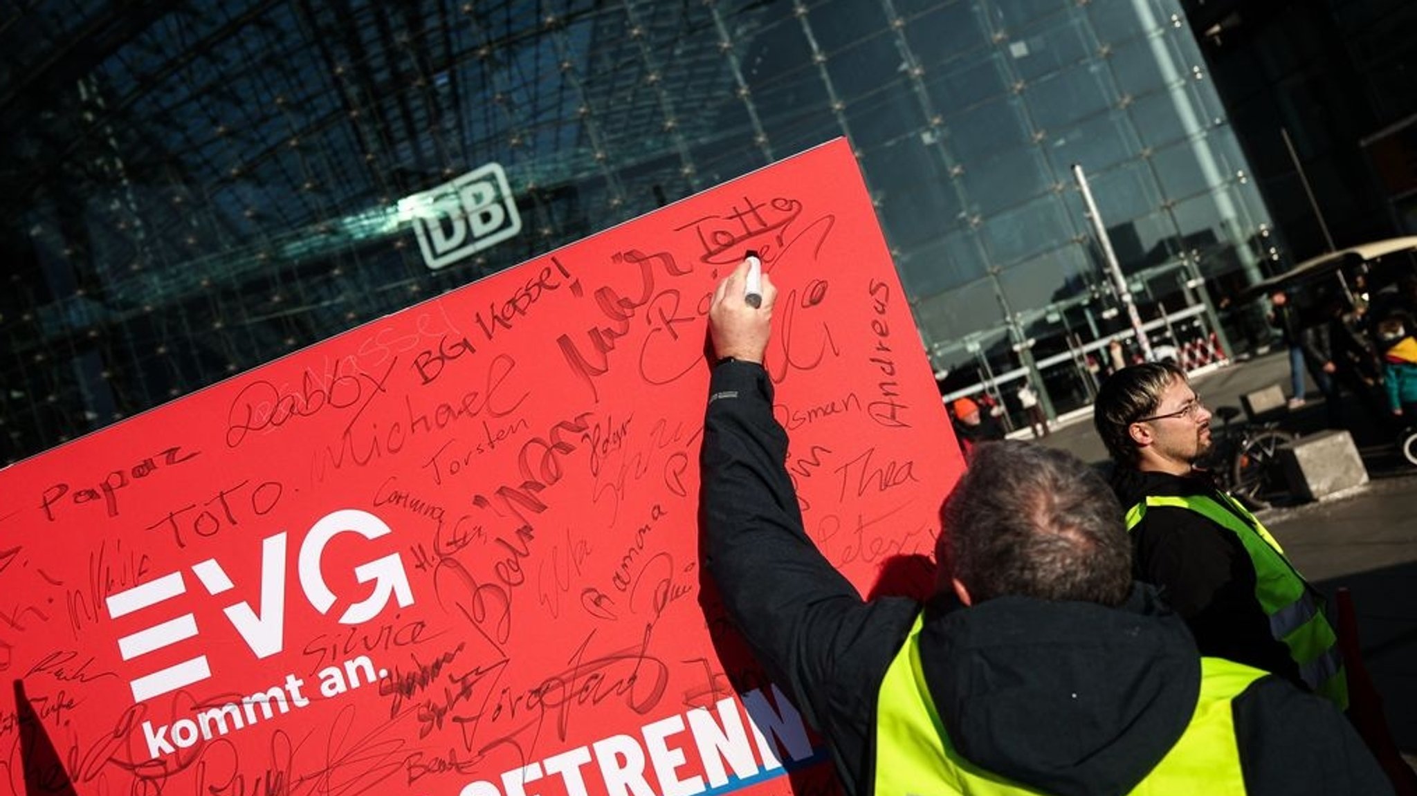 03.02.2025, Berlin: Ein Teilnehmer der Kundgebung unterschreibt auf einem Aufsteller mit EVG-Logo. Die Eisenbahn- und Verkehrsgewerkschaft (EVG) hatte zu einer Kundgebung vor dem Berliner Hauptbahnhof aufgerufen. Foto: Hannes P. Albert/dpa +++ dpa-Bildfunk +++