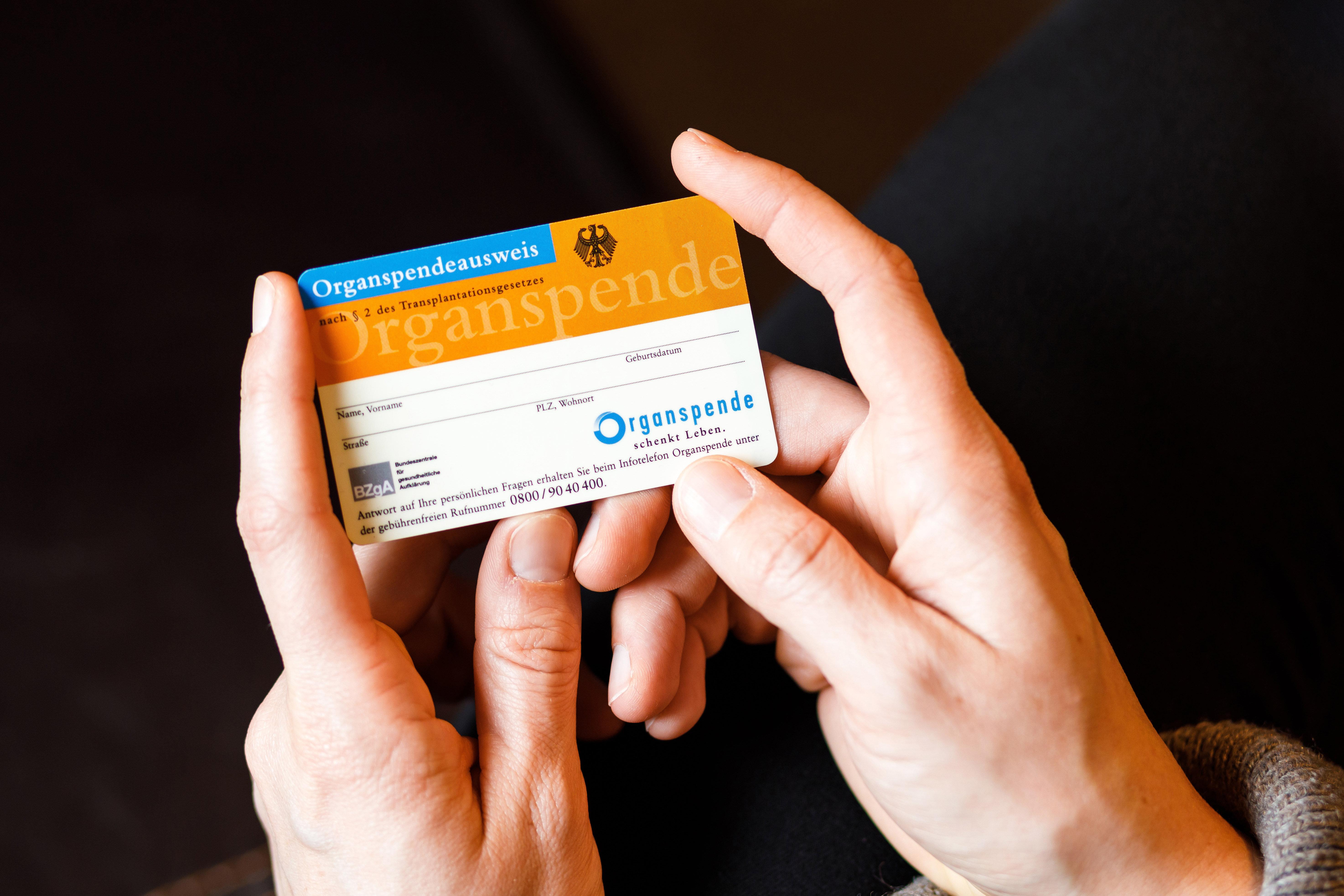 Eine Frau hält einen Organspendeausweis in den Händen.