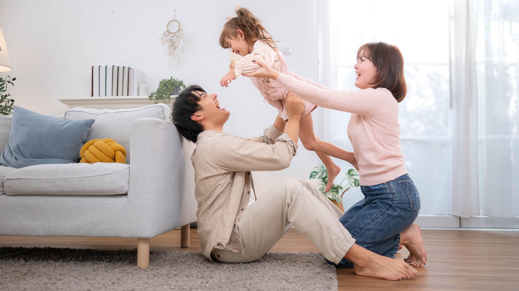 Glückliche junge Familie verbringen Qualität Zeit zusammen zu Hause, Vater heben kleine Tochter spielerisch, während Mutter unterstützt | Bild: picture alliance / Zoonar | Wosunan Photostory Glückliche junge Familie verbringen Qualität Zeit zusammen zu Hause, Vater heben kleine Tochter spielerisch, während Mutter unterstützt