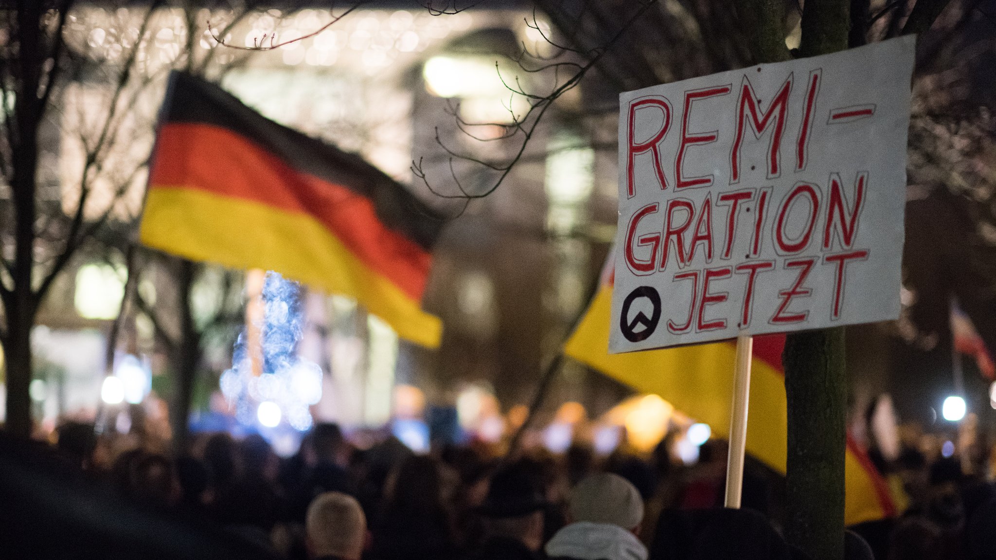 Schild mit der Aufschrift "Remigration jetzt" und dem Symbol der Identitären Bewegung