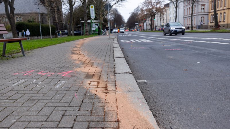 In Gießen sind an der Bushaltestelle Johanneskirche auf dem Gehweg Bindemittel sowie Markierungen der Spurensicherung auf Gehweg und Fahrbahn zu sehen. | Bild: picture alliance/dpa | Christian Lademann In Gießen sind an der Bushaltestelle Johanneskirche auf dem Gehweg Bindemittel sowie Markierungen der Spurensicherung auf Gehweg und Fahrbahn zu sehen.