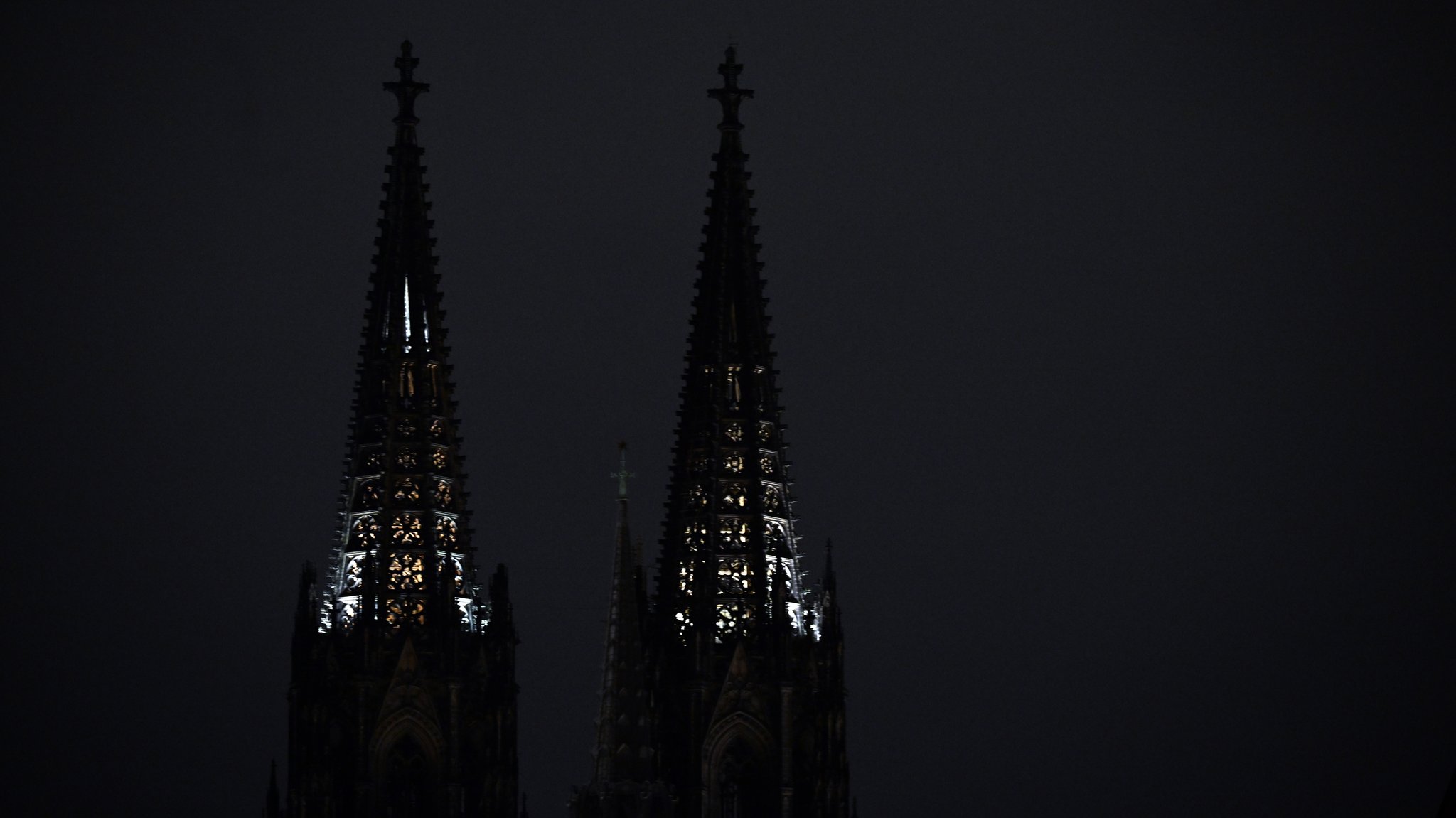 Dunkel hebt sich die Silhouette des Kölner Doms vor dem Nachthimmel ab. 