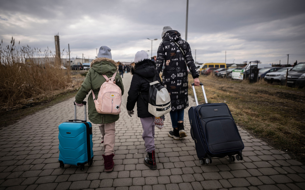 Geflüchtete aus der Ukraine gehen mit ihren Koffern nach dem Grenzübertritt von Schehyni in der Ukraine nach Medyka in Polen.