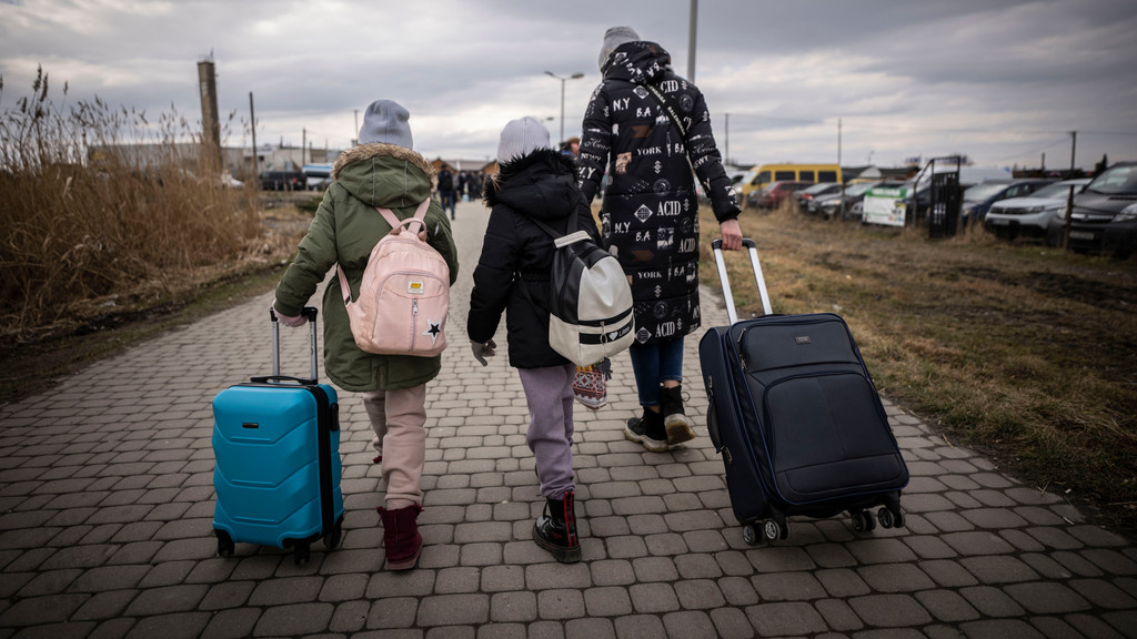 Geflüchtete aus der Ukraine gehen mit ihren Koffern nach dem Grenzübertritt von Schehyni in der Ukraine nach Medyka in Polen.