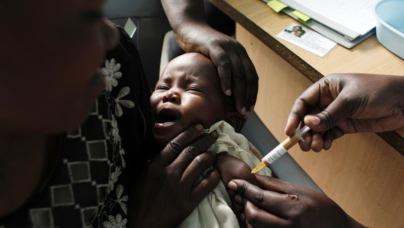 Afrikanisches Baby im Arm seiner Mutter bei einer Malaria-Impfung.