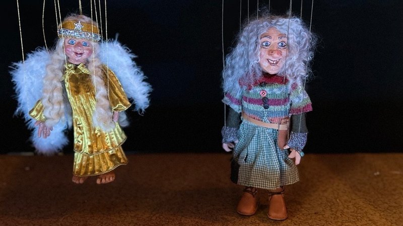 Zwei Marionetten hängen nebeneinander. Eine ist ein Engel, die andere ein Trollfrau. | Bild: BR/Kristina Kreutzer Zwei Marionetten hängen nebeneinander. Eine ist ein Engel, die andere ein Trollfrau.