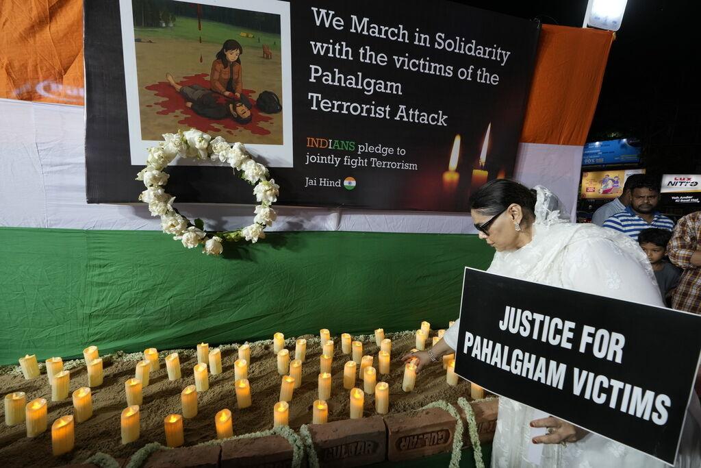 25.04.2025, Indien, Kolkata: Eine Frau stellt eine Kerze und hält ein Transparent während eines Protest- und Solidaritätsmarsches gegen die Ermordung von Touristen durch Militante in der Nähe von Pahalgam im indisch kontrollierten Kaschmir. Foto: Bikas Das/AP/dpa +++ dpa-Bildfunk +++