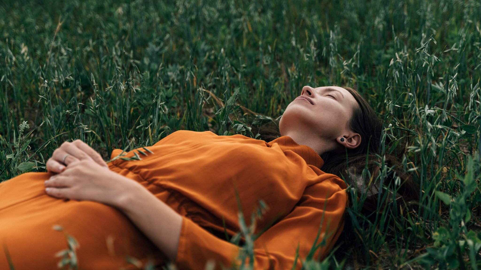 Eine Frau im Kleid liegt im Gras und schaut in den Himmel. | Bild: picture alliance / Westend61 | Oleksandra Troian Eine Frau im Kleid liegt im Gras und schaut in den Himmel.