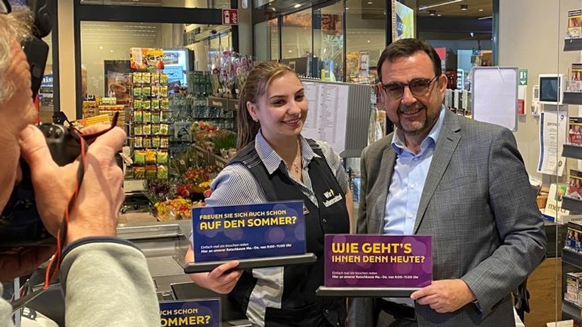 Bayerns Gesundheitsminister Klaus Holetschek steht neben einer Verkäuferin an der Supermarkt-"Ratschkasse" in Buxheim