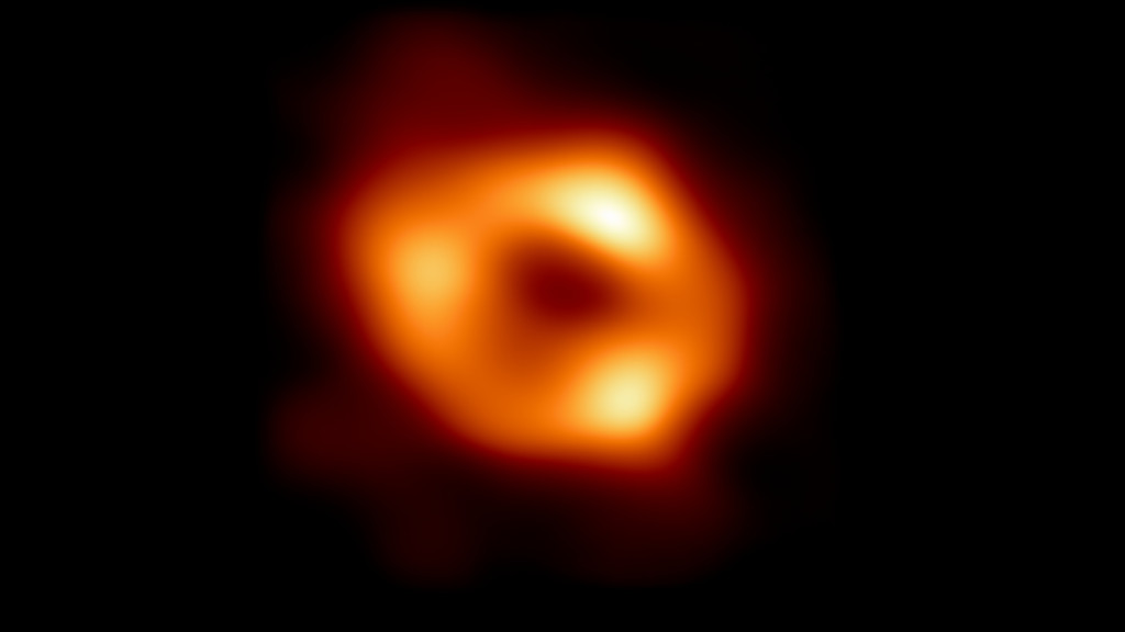 Ein orange-gelblicher Kringel vor einem schwarzen Hintergrund. Das Zentrum des Kringels ist dunkel. Dort befindet sich der Schatten des supermassereichen Schwarzen Lochs Sagittarius A*.