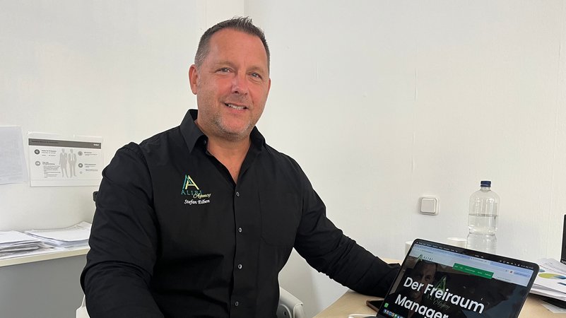 Stefan Einen sitzt im schwarzen Hemd an seinem Schreibtisch am Laptop. | Bild: Astrid Uhr Stefan Einen sitzt im schwarzen Hemd an seinem Schreibtisch am Laptop.