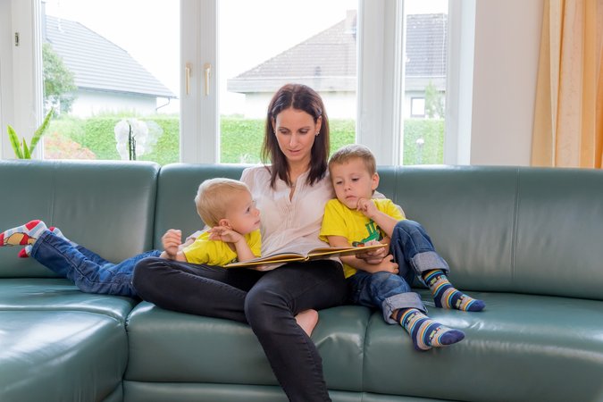 Eine Mutter liest Ihren Kindern ein Märchen aus einem Buch vor.