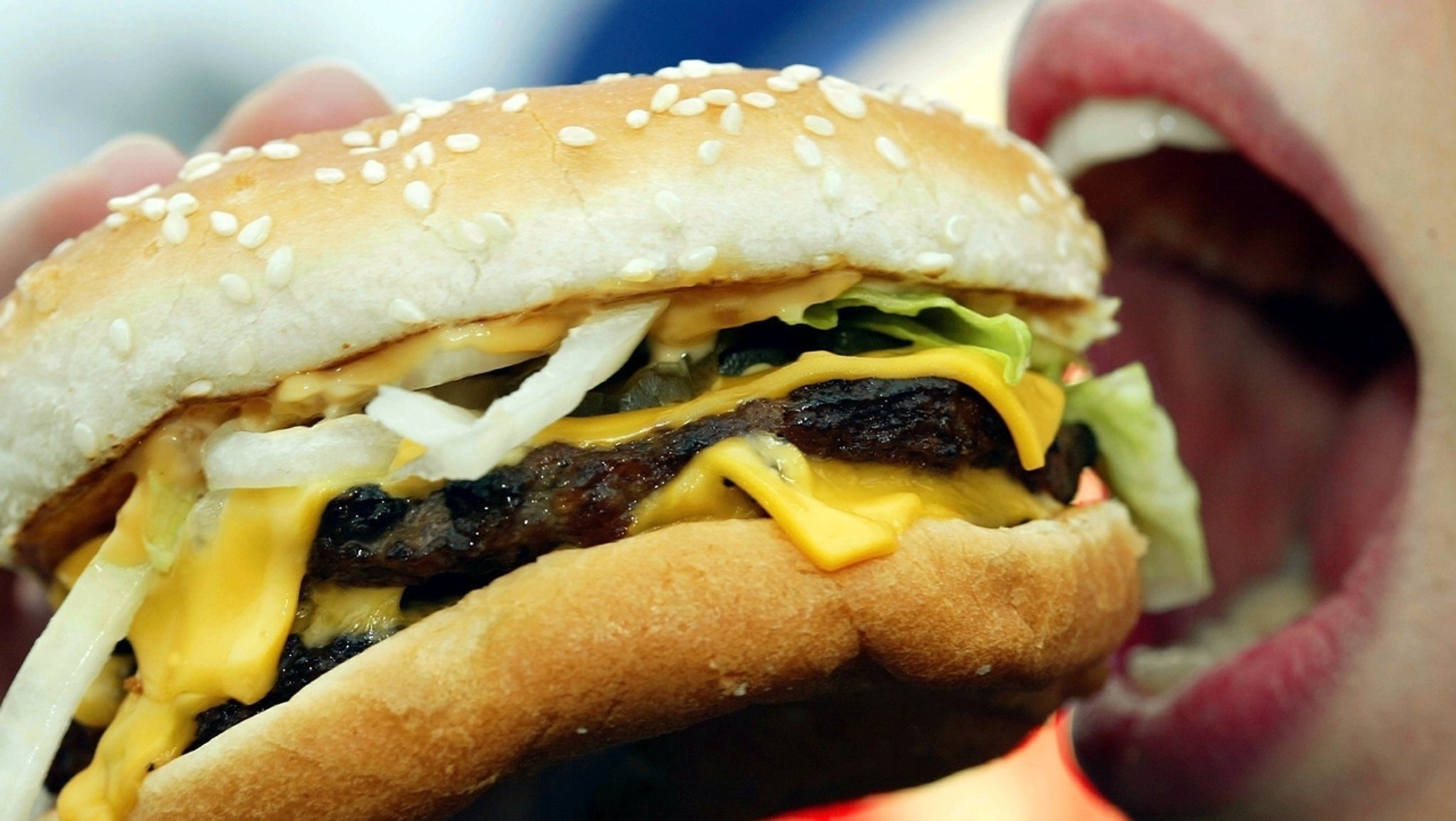 Eine junge Frau isst einen Hamburger. Laut Berechnungen der Forscher um Stephan Klasen von der Universität Göttingen wird sich der Kalorienbedarf bis 2100 um bis zu 80 Prozent erhöhen.