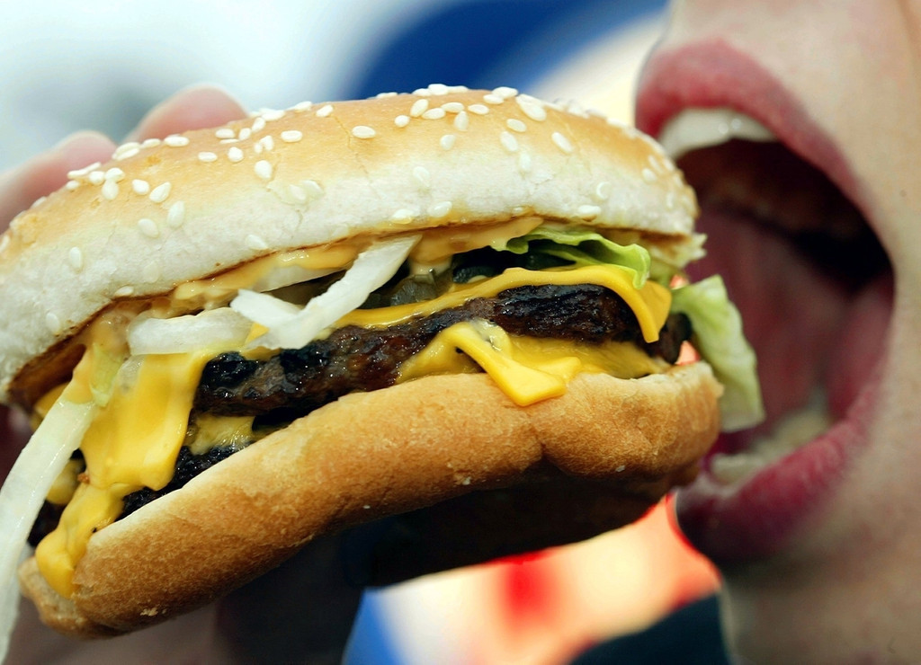 Eine junge Frau isst einen Hamburger. Laut Berechnungen der Forscher um Stephan Klasen von der Universität Göttingen wird sich der Kalorienbedarf bis 2100 um bis zu 80 Prozent erhöhen.