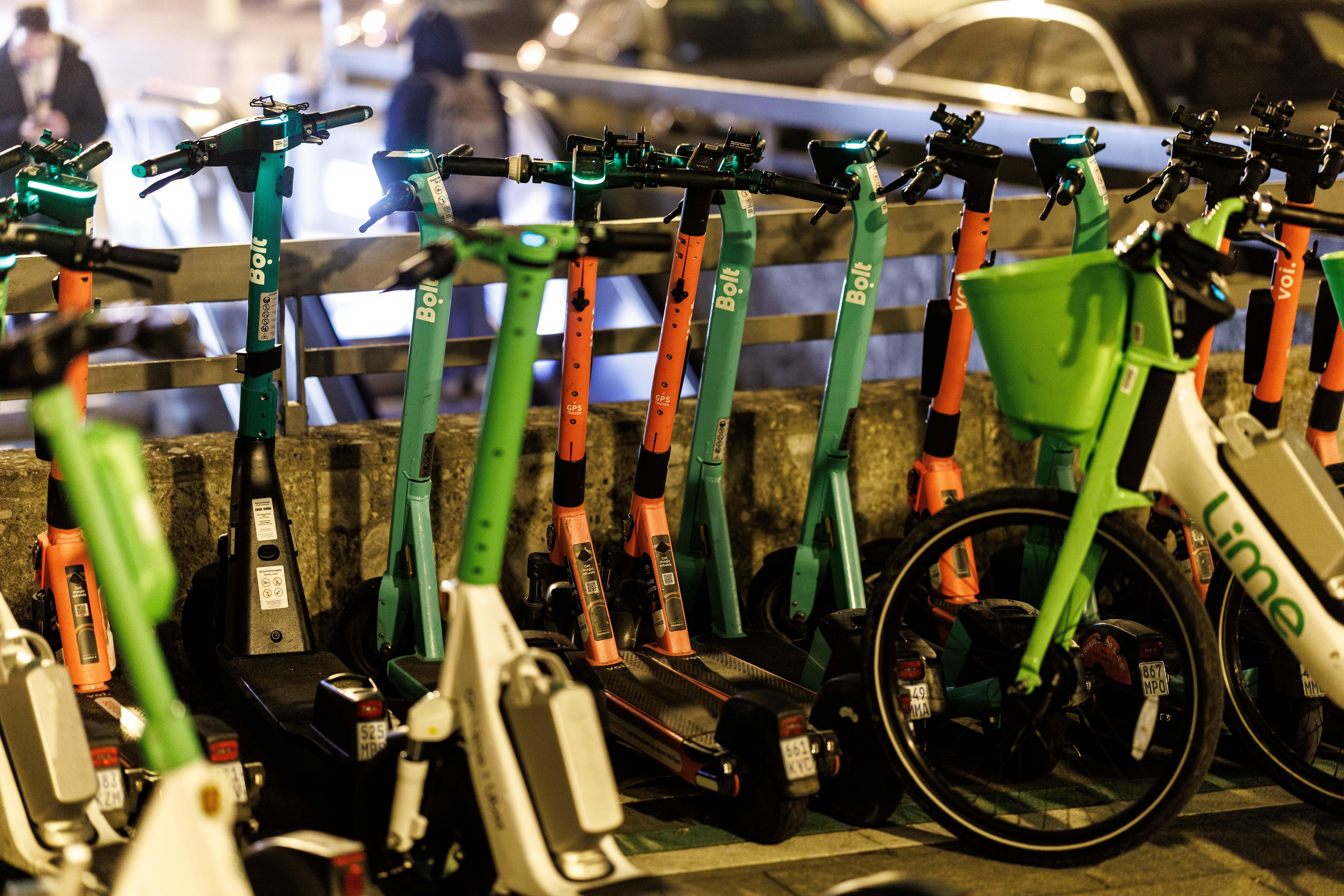 E-Scooter verschiedener Marken stehen an einer U-Bahn Station geparkt.
