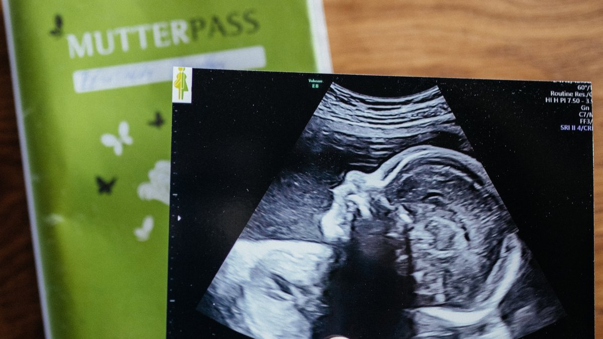 Grüner Mutterpass und Ultraschalbild einer Schwangeren
