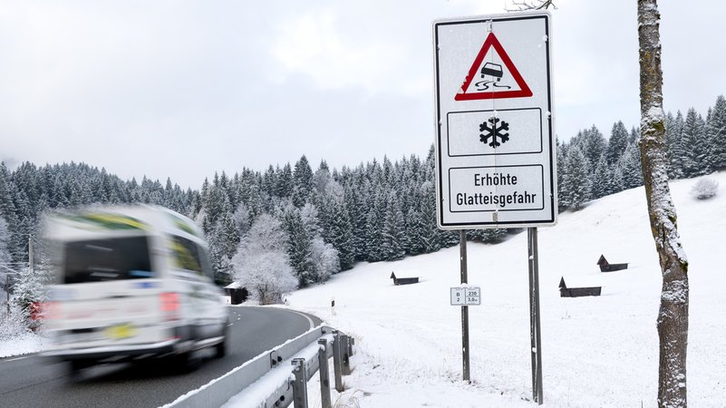 18.11.2025, Bayern, Garmisch-Partenkirchen: Ein Lieferwagen fährt über eine Straße an einem Schild mit der Aufschrift „Erhöhte Glatteisgefahr“ entlang. | Bild: Sven Hoppe/dpa 18.11.2025, Bayern, Garmisch-Partenkirchen: Ein Lieferwagen fährt über eine Straße an einem Schild mit der Aufschrift „Erhöhte Glatteisgefahr“ entlang.
