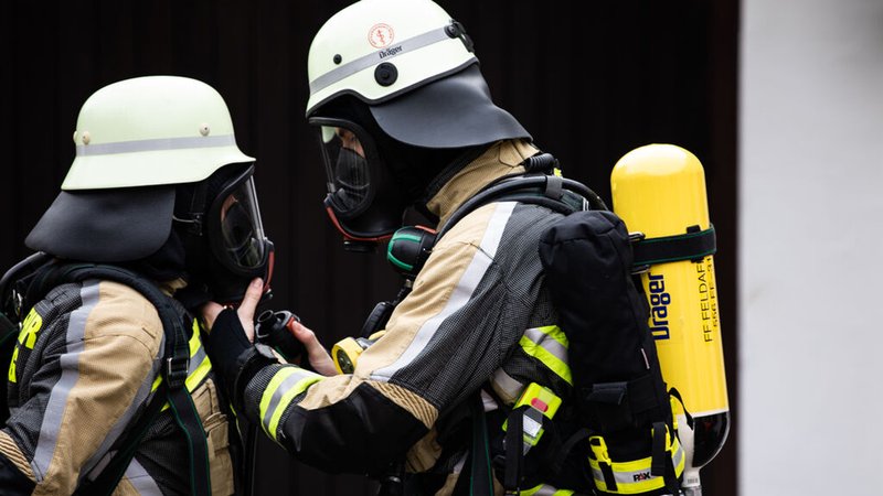 Zwei Mitglieder der Feuerwehr mit Sauerstoffmasken. 
