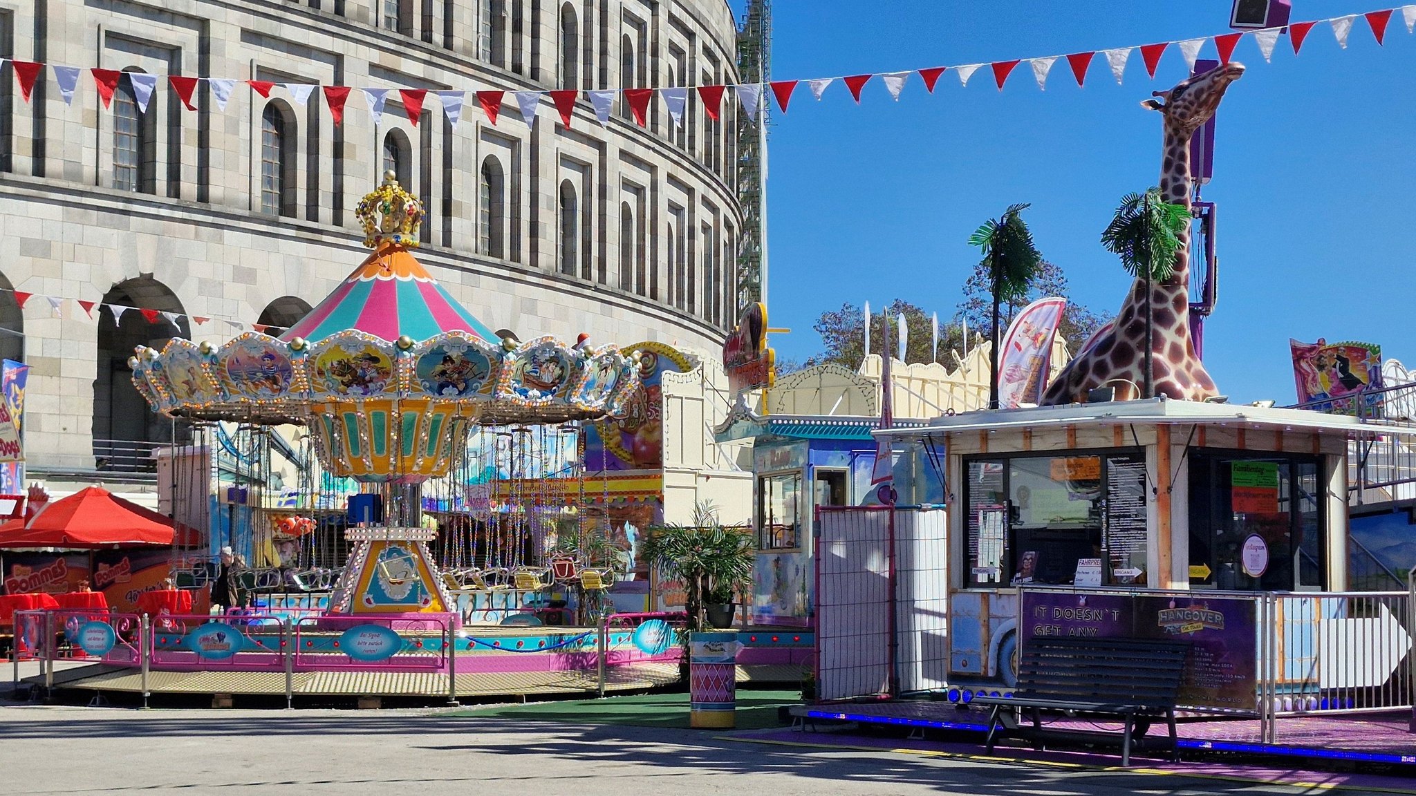 Ein buntes Kinder-Kettenkarussell auf dem Nürnberger Volksfest steht vor dem Dokumentationszentrum Reichsparteitagsgelände.