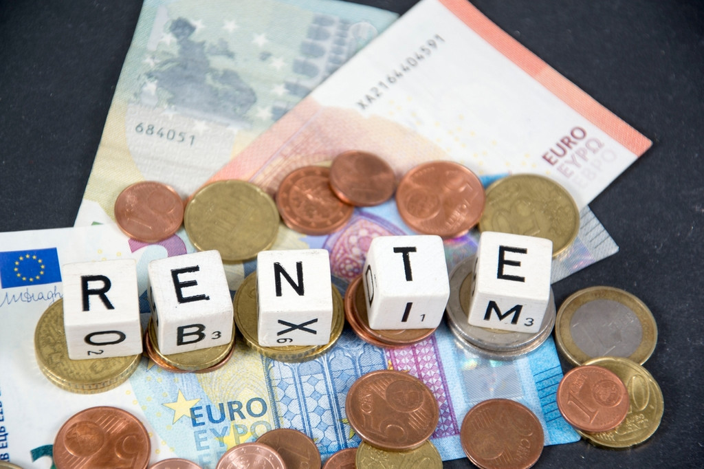 Euroscheine und -münzen, auf denen Würfel liegen auf denen das Wort "Rente" steht (Symbolbild).