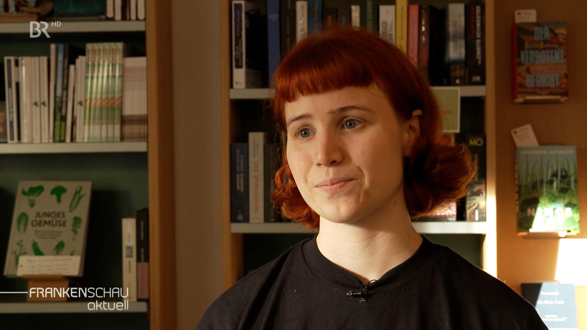 Jana Brammer steht vor einem Bücherregal in ihrem Buchcafé.