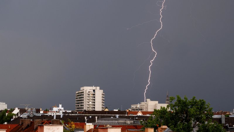 dpatopbilder - 22.06.2023, Bayern, München: Ein Gewitter mit Blitzen zieht in den Abendstunden über die Dächer der bayerischen Landeshauptstadt. Foto: Peter Kneffel/dpa +++ dpa-Bildfunk +++