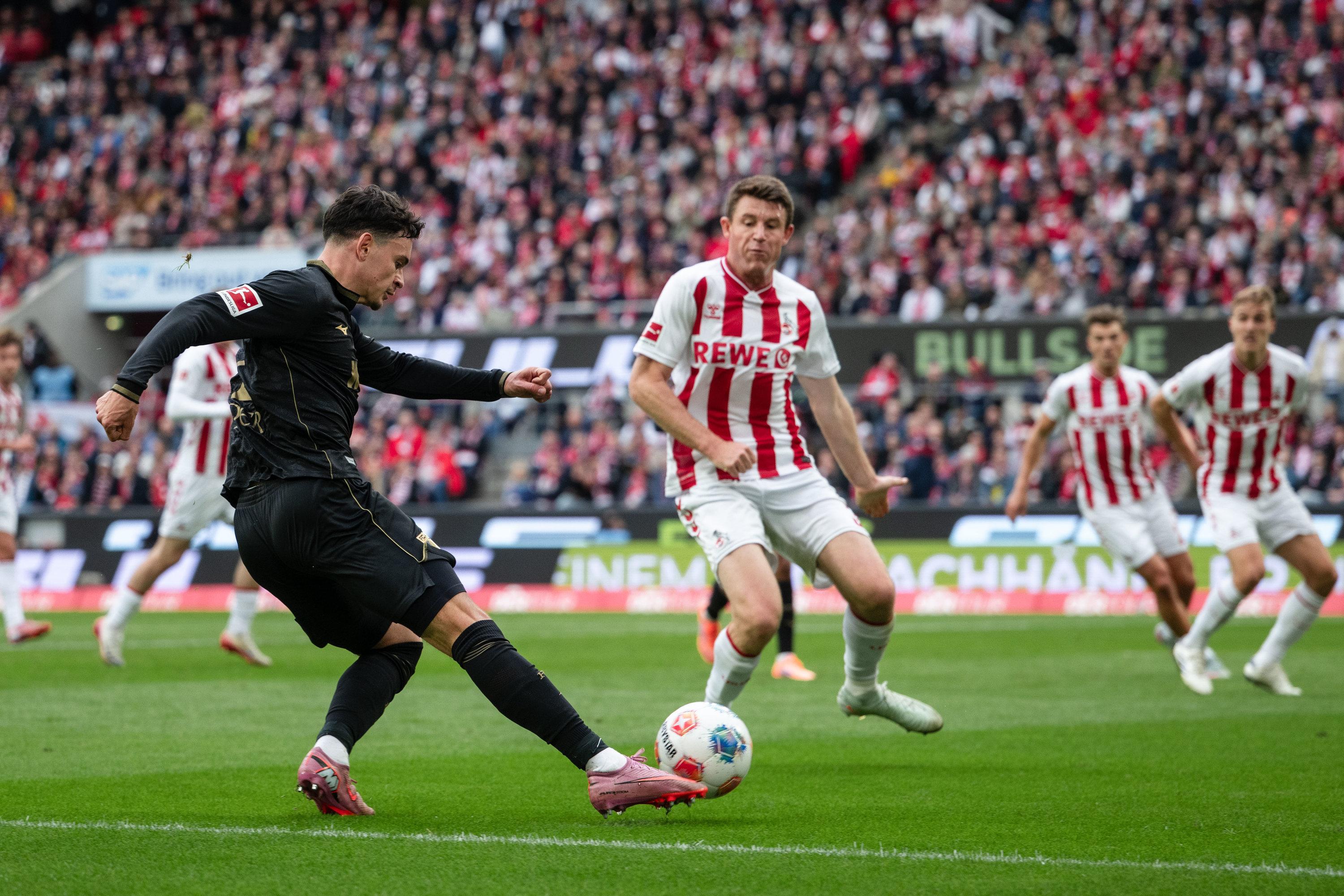 18.10.2025, Nordrhein-Westfalen, Köln: Fußball: Bundesliga, 1. FC Köln - FC Augsburg, 7. Spieltag, RheinEnergieStadion. Fabian Rieder (l, FC Augsburg) spielt den Ball neben Dominique Heintz (1. FC Köln). 