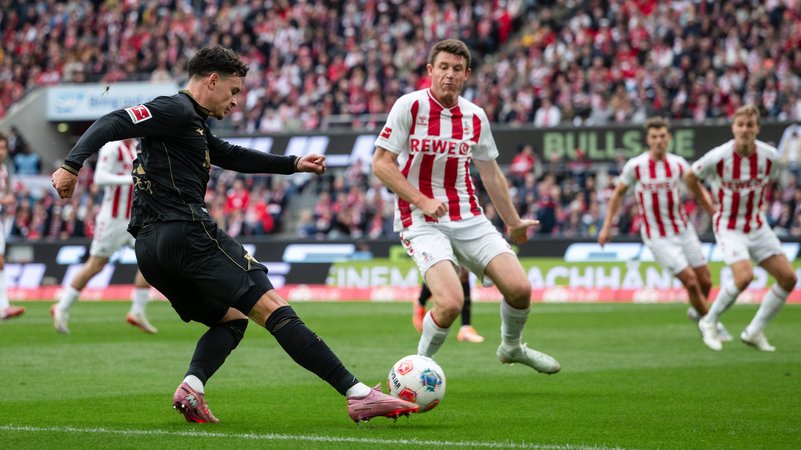 18.10.2025, Nordrhein-Westfalen, Köln: Fußball: Bundesliga, 1. FC Köln - FC Augsburg, 7. Spieltag, RheinEnergieStadion. Fabian Rieder (l, FC Augsburg) spielt den Ball neben Dominique Heintz (1. FC Köln). | Bild: dpa-Bildfunk/Marius Becker 18.10.2025, Nordrhein-Westfalen, Köln: Fußball: Bundesliga, 1. FC Köln - FC Augsburg, 7. Spieltag, RheinEnergieStadion. Fabian Rieder (l, FC Augsburg) spielt den Ball neben Dominique Heintz (1. FC Köln).