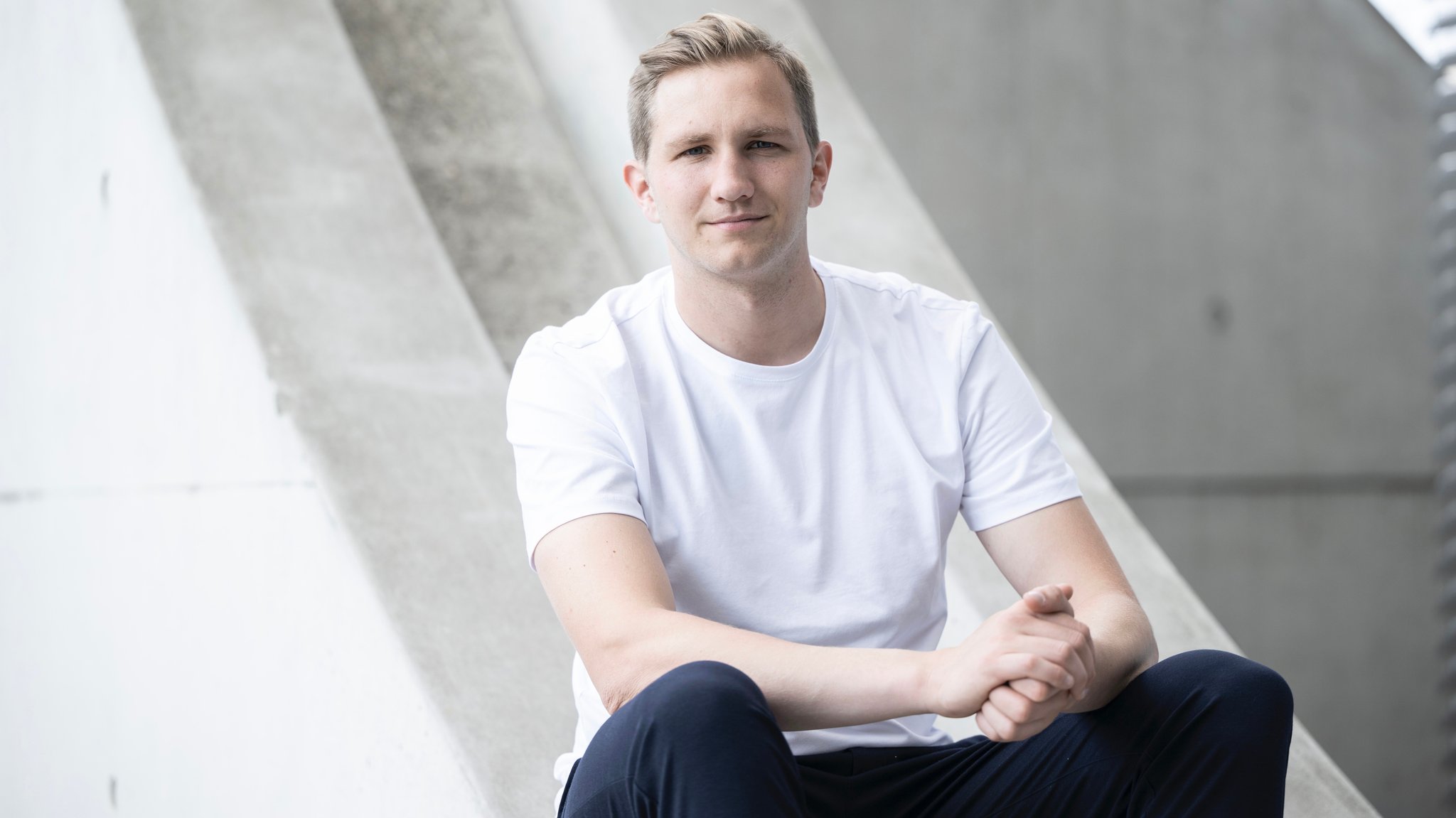 Ein junger Mann mit weißem T-Shirt schaut in die Kamera, es ist Sozialforscher Kilian Hampel