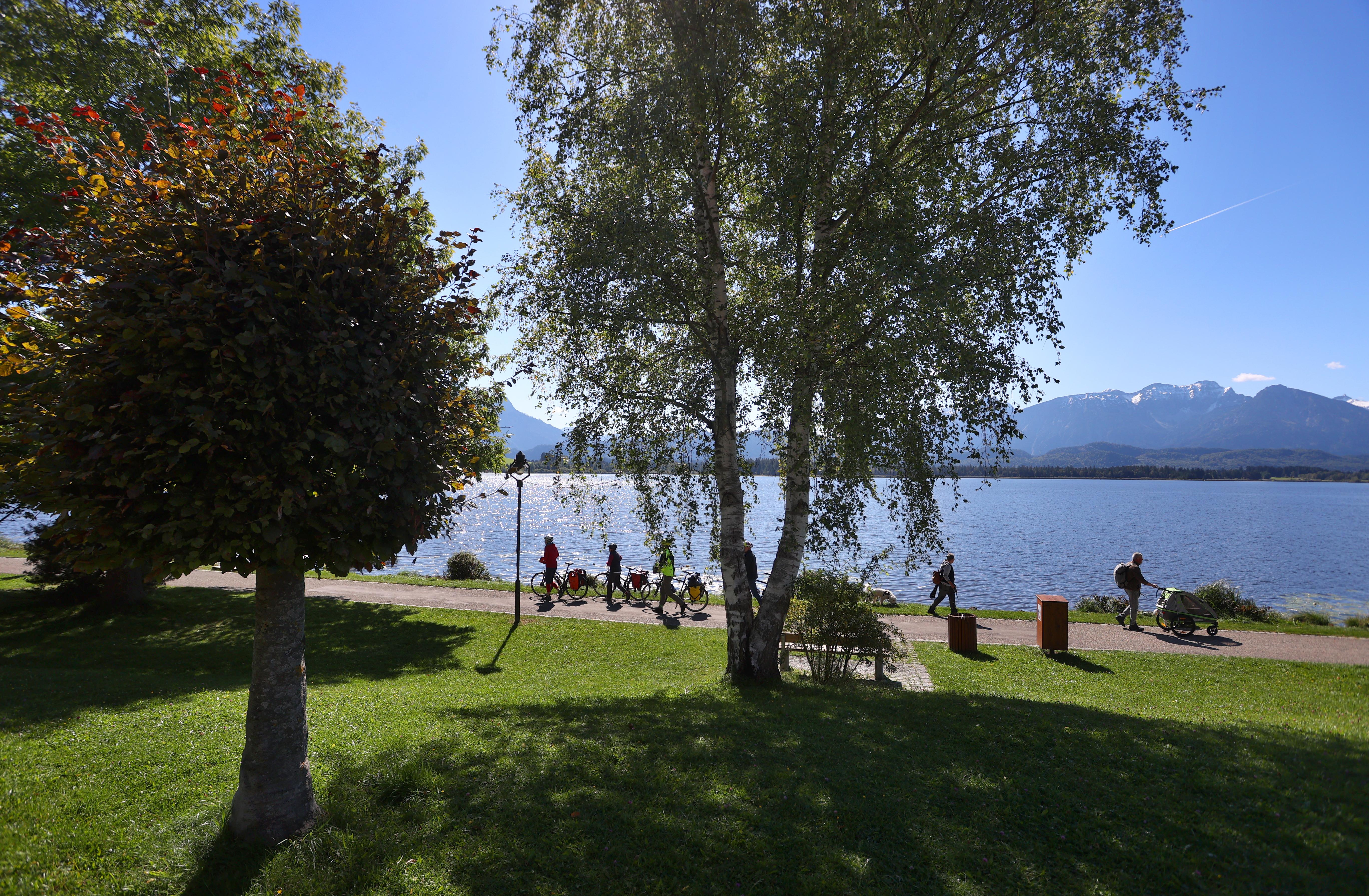Spaziergänger und Fahrradfahrer auf einem Weg am Ufer des Hopfensees.