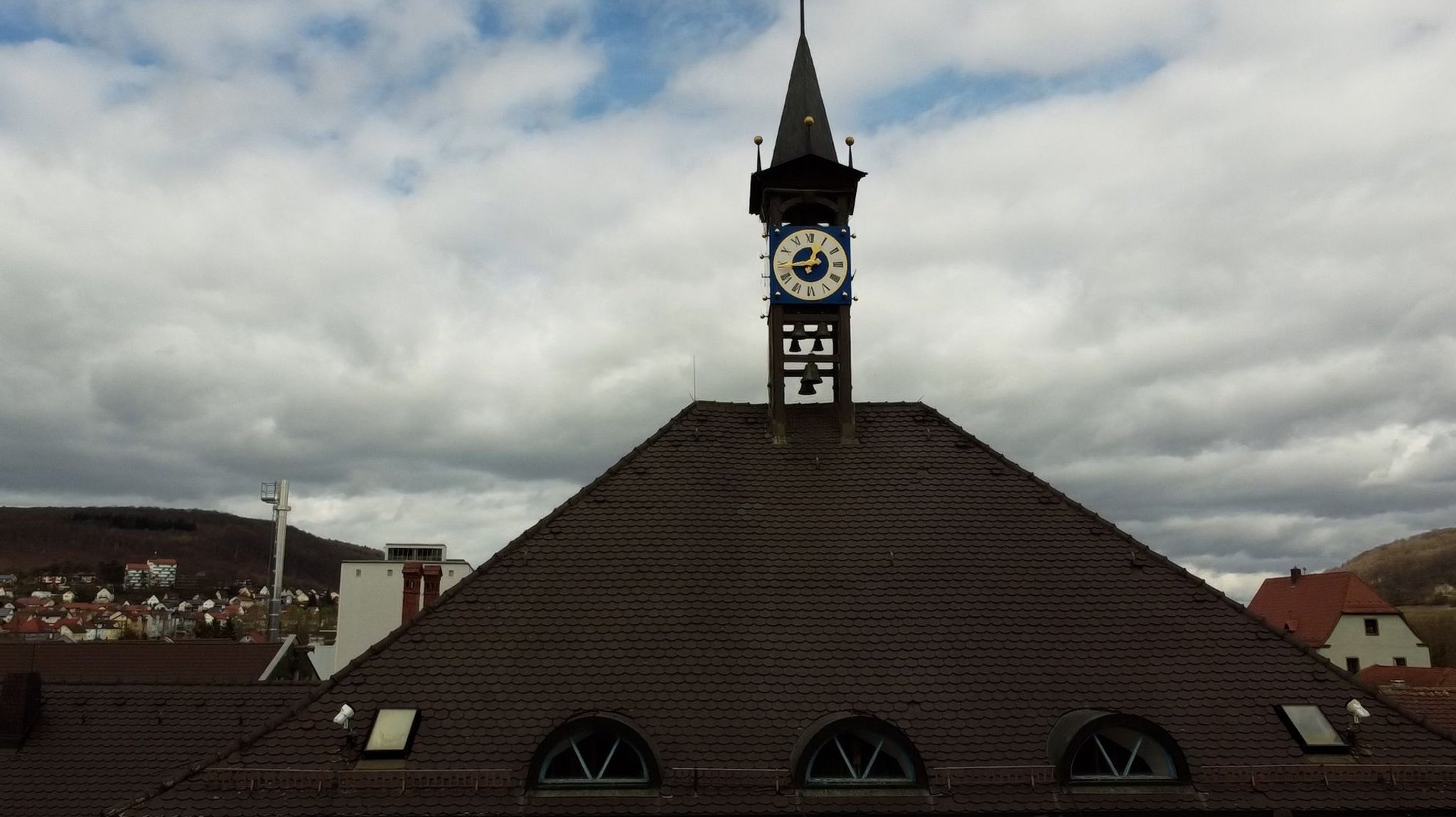 Das Rathausdach in Treuchtlingen mit einer Uhr und Glocken.