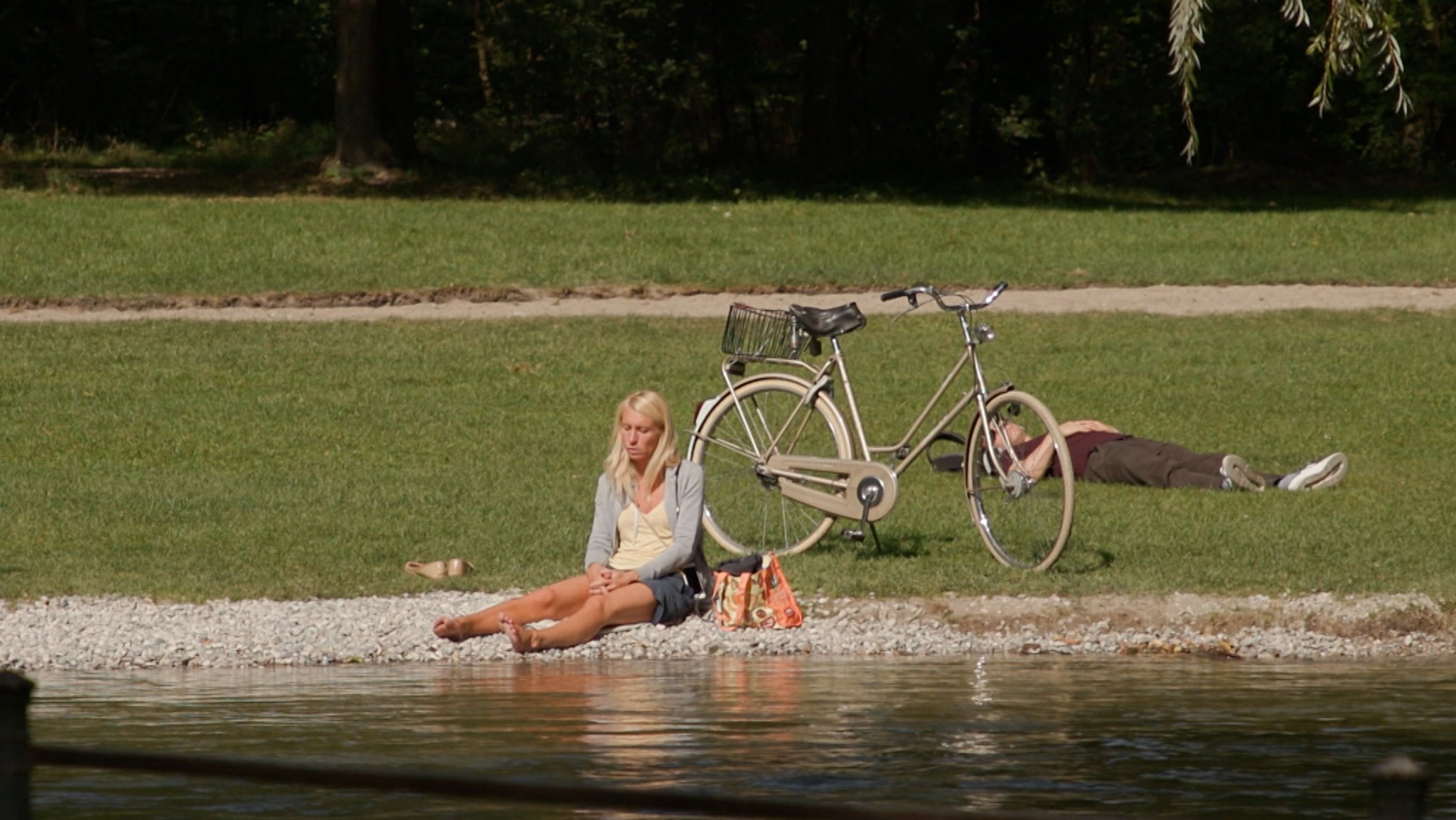 Frau sitzt an der Isar in der Sonne