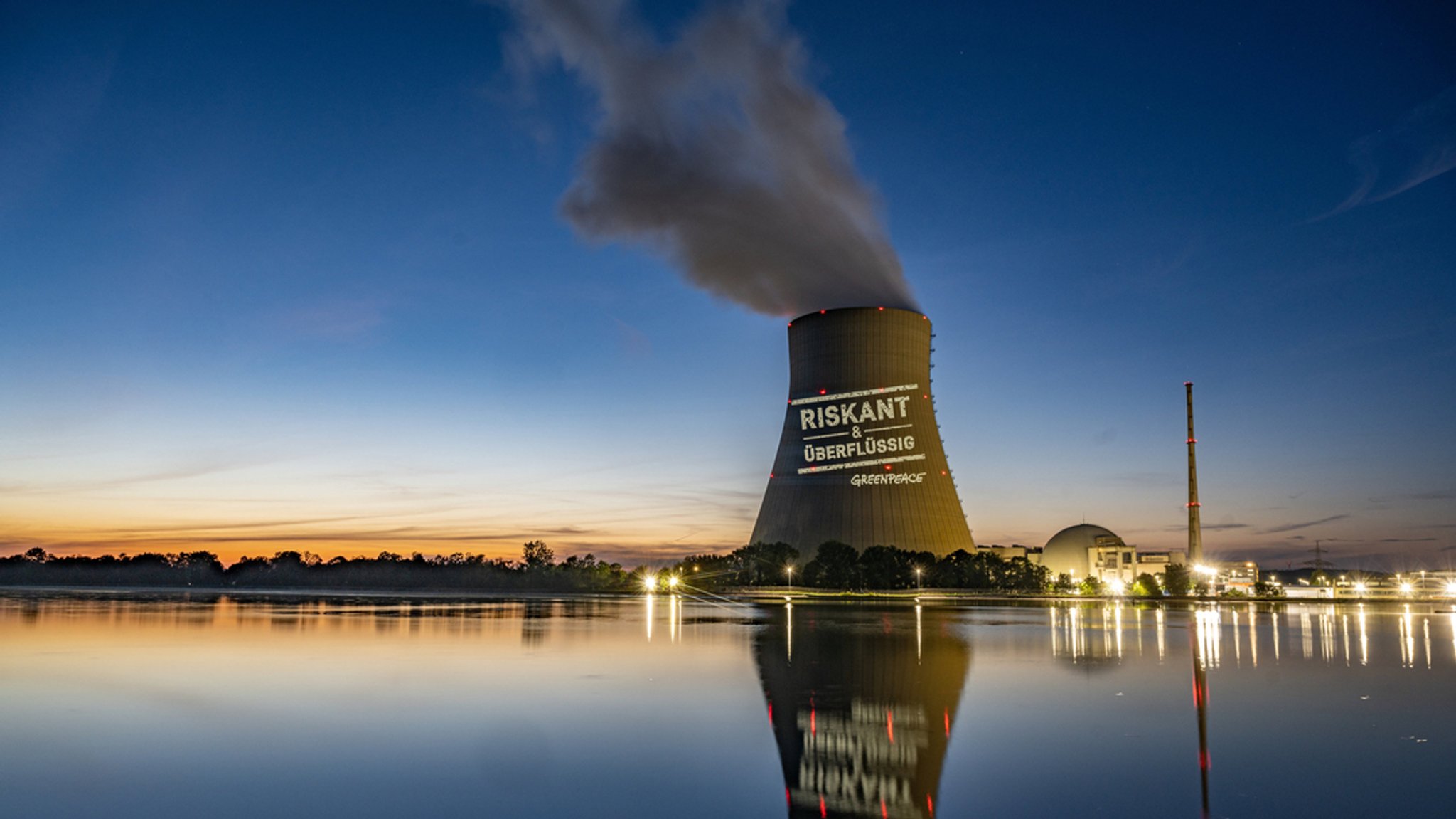 Greenpeace-Aktivisten projizieren "Riskant & überflüssig" an den Kühlturm am Kernkraftwerk Isar 2.