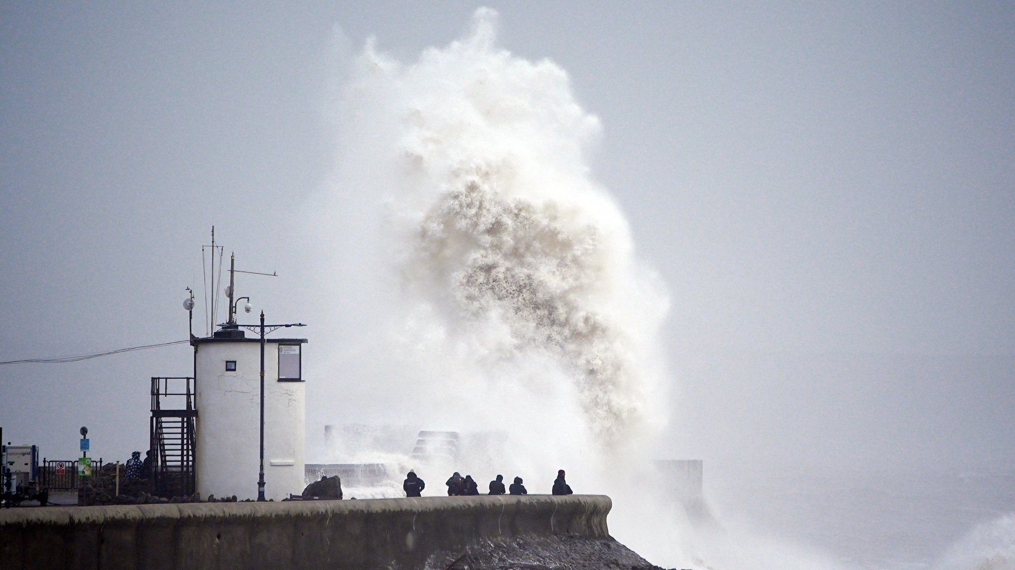 Eine große Welle bricht über die Strandpromenade in Porthcawl in Wales. Wegen Sturm "Darragh" hat das britische Wetteramt eine seltene rote Wetterwarnung herausgegeben. 